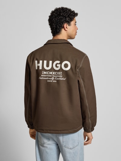 Męski model nosi Regular Fit Bluzon z czystej bawełny Model 'BIYO2611' od Hugo Blue, efekt: jednolity kolor, z wykładanym kołnierzem, zatrzaski, nadruk z logo i szwy w kontrastowym kolorze, długi rękaw, elastyczne zakończenia, tunel na dole, boczne wpuszczane kieszenie oraz kieszeń wewnętrzna, widok na całą sylwetkę z tyłu.