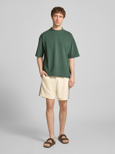 Männermodel trägt Regular Fit Sweatshorts mit elastischem Bund Modell 'RIBER' von Only & Sons, unifarben mit Kontraststreifen, Eingrifftaschen, Ganzkörperansicht von vorne