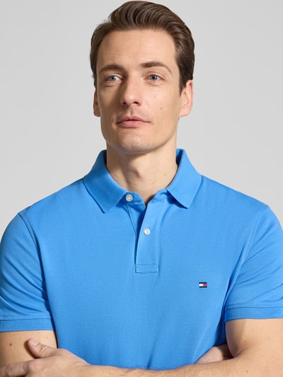 Männermodel trägt Regular Fit Poloshirt aus Baumwoll-Mix von Tommy Hilfiger, Optik: Unifarben, Logo-Stitching, Nahaufnahme Oberkörper.