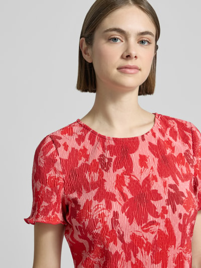 Frauenmodel trägt Slim Fit T-Shirt mit Allover-Muster Modell 'FLORA' von Pieces, florales-Muster, Rundhals, Kurzarm, Plissee, Nahaufnahme Oberkörper.