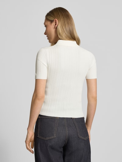 Frauenmodel trägt Slim Fit Strickpullover aus Viskose-Mix Modell 'Sareplette' von HUGO in Strickoptik mit Streifen-Struktur, Polokragen, V-Ausschnitt, Kurzarm, Materialverarbeitung Strick, Farbe Creme, Ganzkörperansicht Rückansicht.
