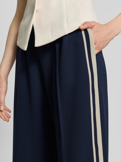 Vrouwenmodel draagt Jog Pants met Franse steekzakken van Jake*s Casual, donkerblauw met beige strepen, materiaalmix met stretch, wide leg fit, elastische band, dames casual broek, detailopname heup en been.
