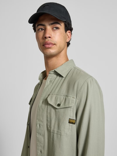 Männermodel trägt Slim Fit Freizeithemd mit Label-Patch Modell 'Marine' von G-Star Raw in Grün, reine Baumwolle, Nahaufnahme Oberkörper.