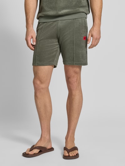 Männermodel trägt Regular Fit Sweatshorts aus Baumwoll-Mix Modell 'TERRANCE' von HUGO, unifarben, Label Patch, Nahaufnahme Oberschenkel.