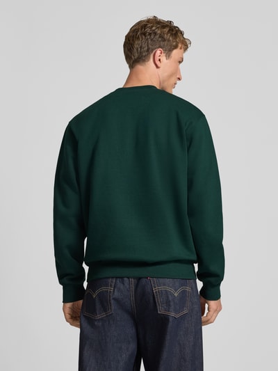 Männermodel trägt Regular Fit Sweatshirt aus Baumwoll-Mix mit Logo-Stickerei von Carhartt Work In Progress in Dunkelgrün, Ganzkörperansicht Rückansicht. Gerippte Abschlüsse, überschnittene Schultern, Rundhalsausschnitt, Rückenlänge 70 cm, Ärmellänge 66 cm.