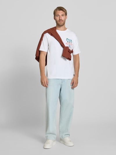 Männermodel trägt Regular Fit T-Shirt aus reiner Baumwolle von Scotch & Soda in Weiß mit Label-Print, Rundhalsausschnitt, Ganzkörperansicht von vorne.
