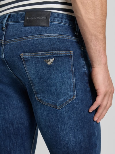 Männermodel trägt Slim Fit Jeans im 5-Pocket-Design von Emporio Armani, blaue Waschung, sichtbare Textur, Nahaufnahme Rückansicht. Elastischer Baumwoll-Mix, Bundweite 41 cm, Innenbeinlänge 82 cm.