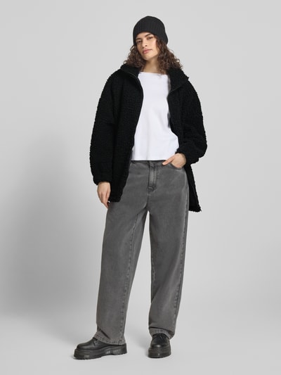 Frauenmodel trägt Jacke aus Teddyfell mit Stehkragen von Karo Kauer, schwarz, oversized, grobe Textur, Reißverschluss, weite Passform, Ganzkörperansicht von vorne.