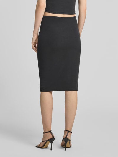 Frauenmodel trägt schwarzen Slim Fit Rock in Knielänge Modell 'Karole' von GUESS aus Elastischer-Material-Mix, Ganzkörperansicht Rückansicht.