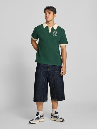 Männermodel trägt Jeans-Bermudas aus reiner Baumwolle Modell 'Double' von Carhartt Work In Progress mit Kontrastnähten, Ganzkörperansicht von vorne, Kontext: Herren Jeans-Bermudas, Loose Fit, 5-Pocket-Design, Bundweite bei Größe M: 44 cm, Innenbeinlänge bei Größe M: 41 cm.