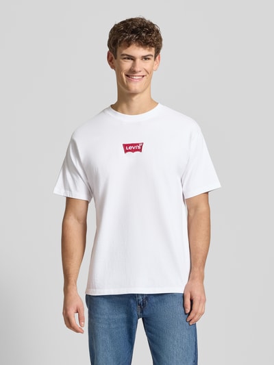 Männermodel trägt T-Shirt mit Label-Detail von Levi's®, reine Baumwolle, lockerer Schnitt, gerippter Rundhalsausschnitt, Ganzkörperansicht von vorne.
