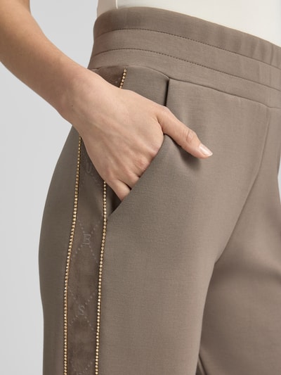 Frauenmodel trägt Slim Fit Sweatpants mit Viskose-Anteil Modell 'Victoire' von GUESS, Zierbesatz, Detailaufnahme Nahaufnahme Oberschenkel.