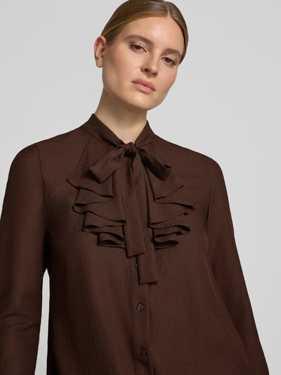 Frauenmodel trägt Regular Fit Schluppenbluse mit Rüschen von Christian Berg Woman Selection in Dunkelbraun, feine Struktur, Nahaufnahme Oberkörper. Rückenlänge 57 cm, Ärmellänge 60 cm, Knopfleiste sichtbar.