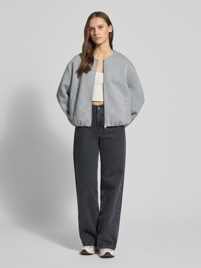 Vrouwenmodel draagt Regular Fit Sweatjacke met Viskose-Anteil Modell 'ELLIE' van Only, uni grijs, zonder kraag, lange mouw, zijzakken, materiaal-mix, vooraanzicht volledig lichaam.