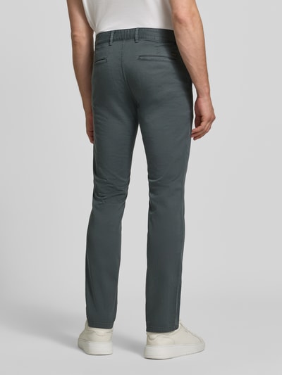 Männermodel trägt Slim Fit Chino aus Baumwoll-Mix Modell 'Chino Slim' von BOSS für BOSS Orange, dunkelgrau, glatte Struktur, Ganzkörperansicht Rückansicht.