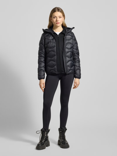 Modelka kobieca nosi Softshell-Jacke mit Kapuze Modell 'RIDER' von PEAK PERFORMANCE, czarny materiał-mix ze stretchem, krój regular fit, zamek, detal z logo, widok całej sylwetki z przodu