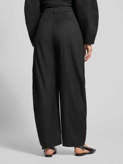 Frauenmodel trägt Barrel Fit Hose mit Viskose-Anteil Modell 'Callia' von Gestuz, schwarz mit Bundfalten, Ganzkörperansicht Rückansicht. Elastischer Material-Mix, Haken- und Reißverschluss, Bundweite 37 cm, Innenbeinlänge 76 cm.