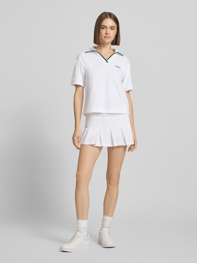 Frauenmodel trägt weißes Regular Fit Poloshirt mit Logo-Stitching von adidas Sportswear aus Baumwolle, Polo-Kragen, Ganzkörperansicht von vorne.