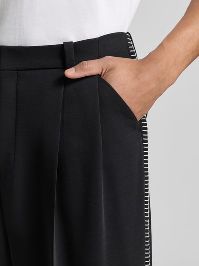 Männermodel trägt Wide Fit Hose mit Bundfalten und Schurwoll-Anteil Modell 'FEDIX' von HUGO, Two-Tone-Optik, Twill, Nahaufnahme Oberkörper.