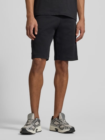 Männermodel trägt schwarze Shorts mit elastischem Bund von EA7 Emporio Armani aus Baumwoll-Mix, Regular Fit, Nahaufnahme Oberschenkel.