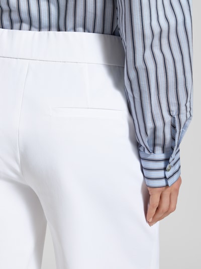 Frauenmodel trägt Schlupfbermuda Techno Cotton Superstretch von Raffaello Rossi, krój regular fit, elastyczny pas, kieszenie z tyłu, model 'ISKA', szerokość w rozmiarze 36: 39 cm, długość wewnętrzna nogawki w rozmiarze 36: 24 cm, biała tkanina, struktura gładka, widoczne delikatne paski koszuli, detaliczny widok z tyłu