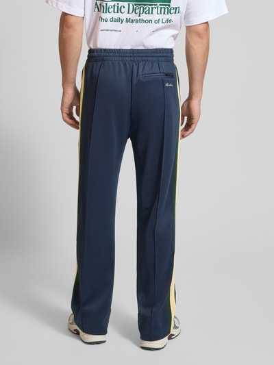Männermodel trägt Track Pants mit Reißverschlusstaschen und Kordelzug von ANOTHER COTTON LAB im Material-Mix Wide-Fit, Ganzkörperansicht Rückansicht.