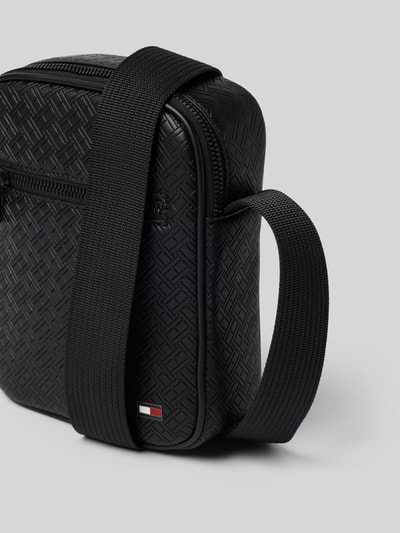 Produktfoto, schwarze Umhängetasche mit Logo-Detail Modell 'EMBOSSED FLAG' von Tommy Hilfiger in Lederoptik, Flag-Monogrammprägung, aus Kunstleder, sichtbarer Reißverschluss und Schulterriemen