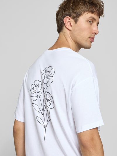 Männermodel trägt Relaxed Fit T-Shirt aus reiner Baumwolle Modell "DYLAN" von JACK & JONES mit floralem Print-Detail, Rückenansicht.