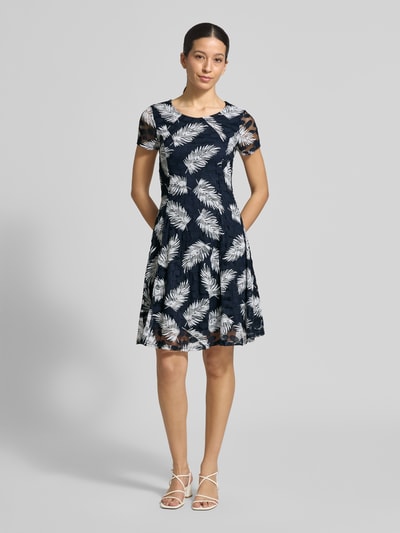Vrouwenmodel draagt Knielanges Kleid mit Rundhalsausschnitt van Apricot, materiaal-mix met stretch, getailleerde fit, knielengte, ronde hals, ruches, donkerblauw met wit bladmotief, voorkant volledig te zien, Ganzkörperansicht von vorne.