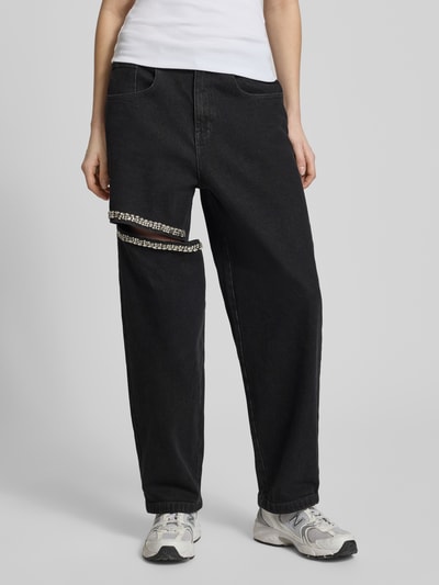 Frauenmodel trägt Straight Fit Jeans mit Cut Out von Karo Kauer aus schwarzem Baumwoll-Elasthan-Mix, 5-Pocket-Design, Ziersteinbesatz, Ganzkörperansicht von vorne.