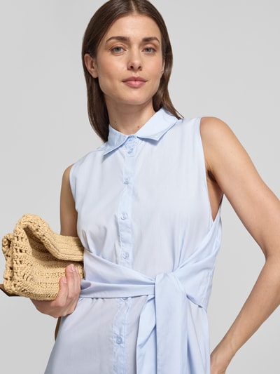 Vrouwenmodel draagt lichtblauw overhemdjurk met strikceintuur, mix van katoen en lyocell, model 'CHIARA' van ECOALF, knoopsluiting, overhemdkraag, A-lijn, midi-jurk, detailopname bovenlichaam.