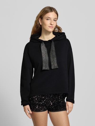 Modelka nosi Regular Fit Hoodie aus Baumwoll-Mix Modell 'CHILLI' od Pieces, czarny, gładki, długi rękaw, bawełniany materiał, zbliżenie na górną część ciała