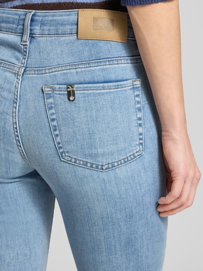 Frauenmodel trägt Flared Fit Jeans im 5-Pocket-Design Modell 'Fly' von Liu Jo White aus elastischem Baumwoll-Mix in Hellblau, Detailaufnahme Rückansicht.