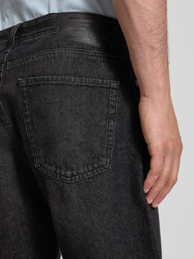 Männermodel trägt Loose Fit Jeansshorts mit Eingrifftaschen Modell 'TONY' von Jack & Jones in Schwarz im Used-Look aus reiner Baumwolle, Detailaufnahme Rückansicht.