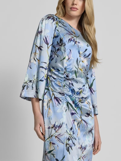Frauenmodel trägt Midikleid aus Seiden-Mix mit Raffungen von Marc Cain in Blau mit floralem Muster, taillierter Schnitt, Rundhalsausschnitt, Rückseitiger Reißverschluss, Stretch-Anteil, Rückenlänge 120 cm, Brustweite 43 cm, Ärmellänge 51 cm, Nahaufnahme Oberkörper.