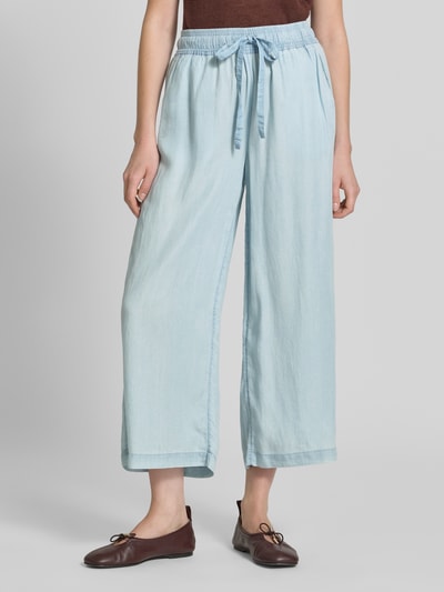 Frauenmodel trägt Wide Fit Stoffhose aus reinem Lyocell in Denim-Optik von Soyaconcept, Hellblau, elastischer Bund mit Tunnelzug, verkürzte Passform, Ganzkörperansicht von vorne.