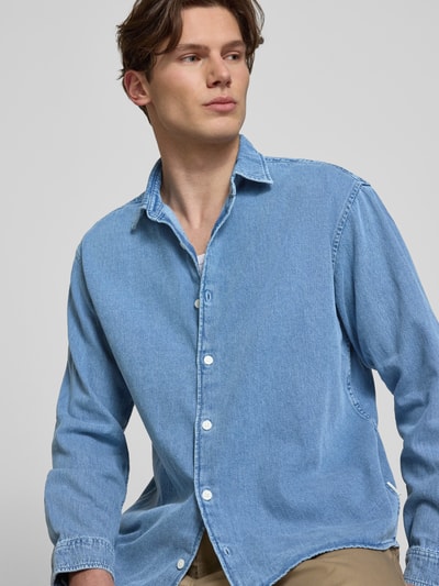 Männermodel trägt Regular Fit Jeanshemd mit Kentkragen Modell 'NORREBRO' von Jack & Jones aus reiner Baumwolle in Hellblau, Nahaufnahme Oberkörper.