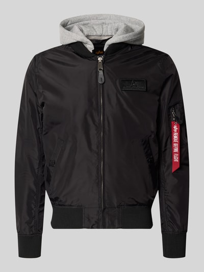 Produktfoto, schwarzer Blouson mit grau melierter Sweat-Kapuze, Armtasche mit rotem Logo-Anhänger, Alpha Industries Blouson mit Logo-Anhänger Modell 'MA-1 TT', lockere Passform, elastische Abschlüsse, Label-Patch, Reißverschluss, glatte Textur