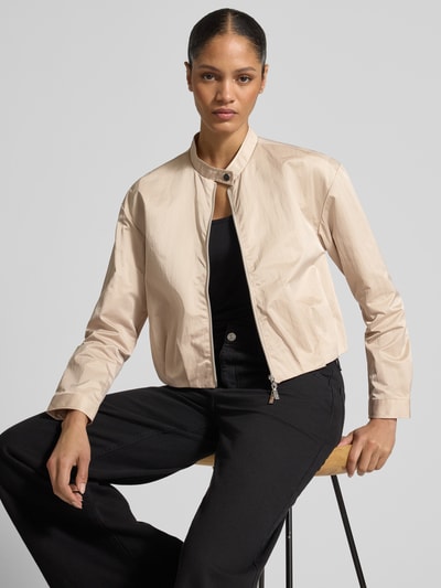 Vrouwenmodel draagt Cropped Jacke mit Zweiwege-Reißverschluss van monari in beige met opstaande kraag en knoopsluiting, ruglengte maat 36: 49 cm, schouderbreedte 50 cm, borstwijdte 44 cm, mouwlengte 56 cm, Ganzkörperansicht van voren.