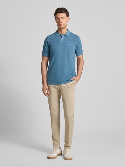 Männermodel trägt Poloshirt aus Baumwolle von MARC O’POLO DENIM in Blau, gerader Schnitt, Piqué, Logo, Ganzkörperansicht von vorne.