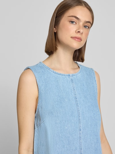 Frauenmodel trägt Relaxed Fit Jeanskleid aus reiner Baumwolle Modell 'FLORA' von Pieces, Denim-Optik, Mini-Länge, Rundhals, ohne Ärmel, Öse und Knopf, Nahaufnahme Oberkörper.