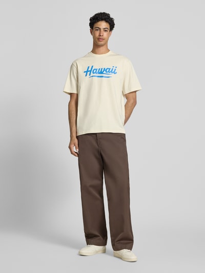 Männermodel trägt Relaxed Fit T-Shirt aus reiner Baumwolle Modell 'RICO' von Only & Sons, unifarbenes Jersey mit Motiv-Print, Ganzkörperansicht von vorne.