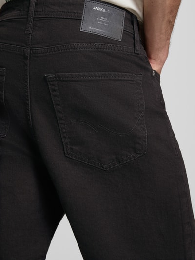 Männermodel trägt Relaxed Fit Jeansshorts Modell 'TONY' von Jack & Jones aus schwarzem Baumwoll-Elasthan-Mix mit Eingrifftaschen, Detailaufnahme Rückansicht. Bundweite 42 cm, Innenbeinlänge 21 cm bei Größe M.