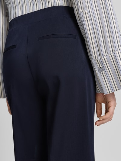 Frauenmodel trägt dunkelblaue Stoffhose mit Gesäßleistentaschen von OPUS PANTS, Baumwoll-Mix, Loose-Fit, Modell 'Mucia Base', Detailaufnahme Rückansicht.