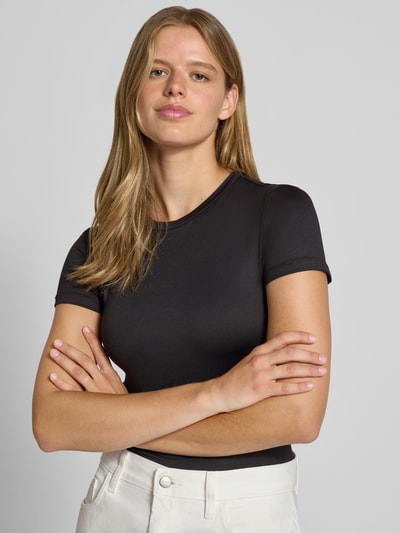 Frauenmodel trägt schwarzes Slim Fit T-Shirt mit Rundhals Modell 'LULA' von PIECES, glatte Textur, Nahaufnahme Oberkörper. Damen T-Shirt.