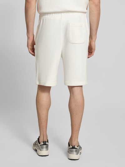 Männermodel trägt Relaxed Fit Sweatshorts aus reiner Baumwolle von Lacoste, unifarben, elastischer Bund, Gesäßtasche, Sweatstruktur, Ganzkörperansicht Rückansicht.