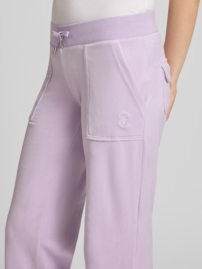 Vrouwenmodel draagt Low Rise Sweatpants met steekzakken model 'LAYLA' van Juicy Couture in lila, materiaalmix met stretch, elastische band, binnenbeenlengte maat S 82 cm, detailopname heup en bovenbeen.