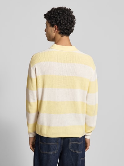Männermodel trägt Regular Fit Strick-Poloshirt mit Block-Streifen von REVIEW, Reine Baumwolle, breite gelb-weiße Streifen, Ganzkörperansicht Rückansicht.