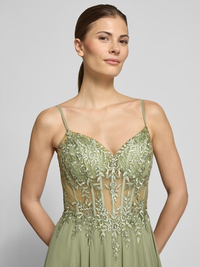 Frauenmodel trägt Abendkleid mit Stitchings und Ziersteinbesatz von Luxuar in zartem Grün, Chiffon, tailliert, Nahaufnahme Oberkörper.