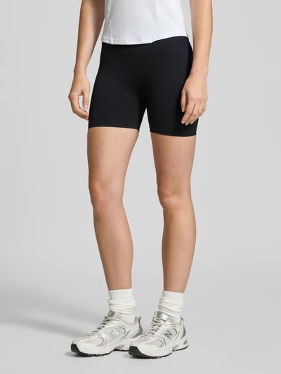Modelka kobieca ma na sobie czarne Radlerhose mit elastischem Bund Modell 'Shape Seamless' od aim'n, materiał z domieszką stretchu, krój slim fit, Szerokość w rozmiarze S: 28 cm, długość nogawki wewnętrznej: 11 cm, zdjęcie całej sylwetki z przodu.